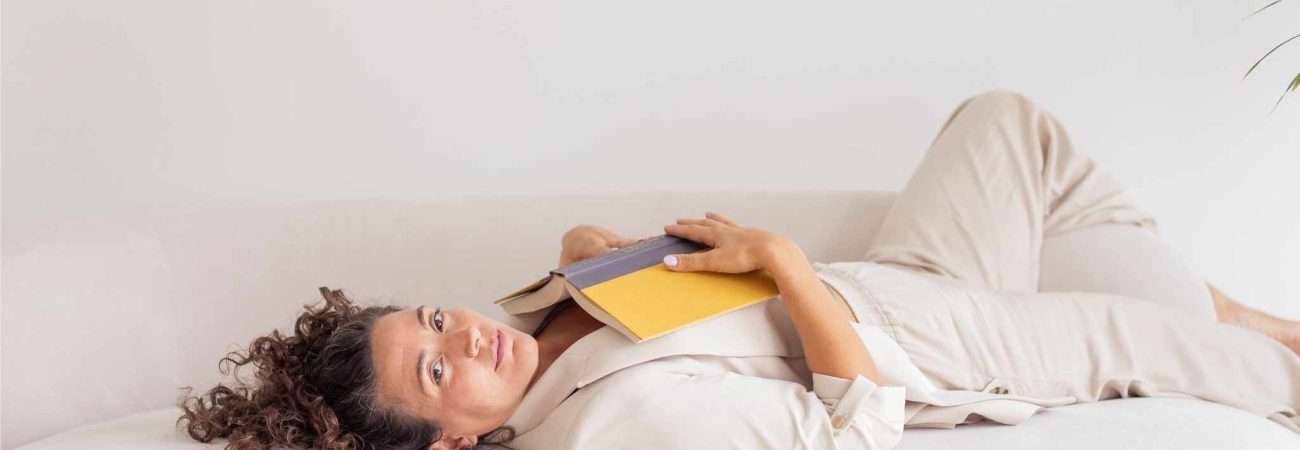 Laurie Ce., coach creativa, tumbada en un sofá con un libro al pecho.